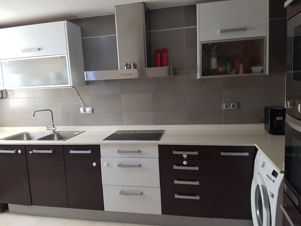 Cocina renovada con encimera clara, muebles bicolor y campana extractora